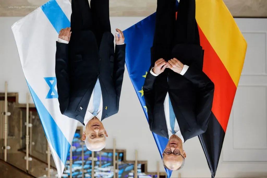 Two men in suits standing near Israeli and European Union flags