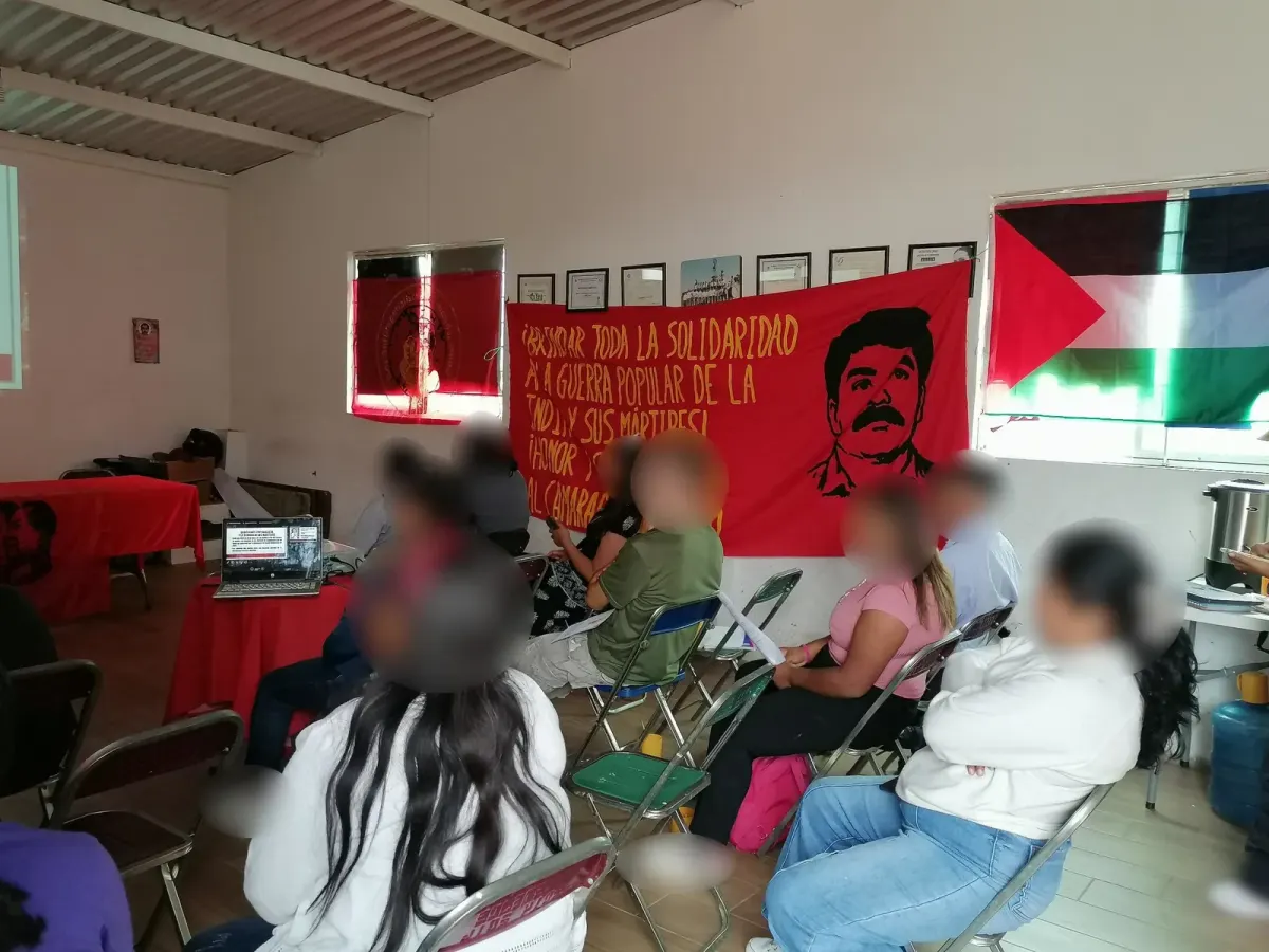 Community meeting with people seated under political banners and a Palestinian flag, suggesting discussion of socialism and freedom in daily life Community meeting with people seated under political banners and a Palestinian flag, suggesting discussion of socialism and freedom in daily life